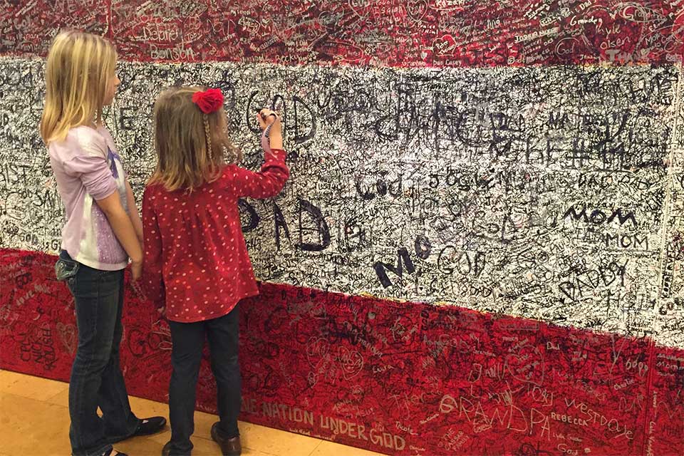 Young girls writing hero message on Hometown Hero painting