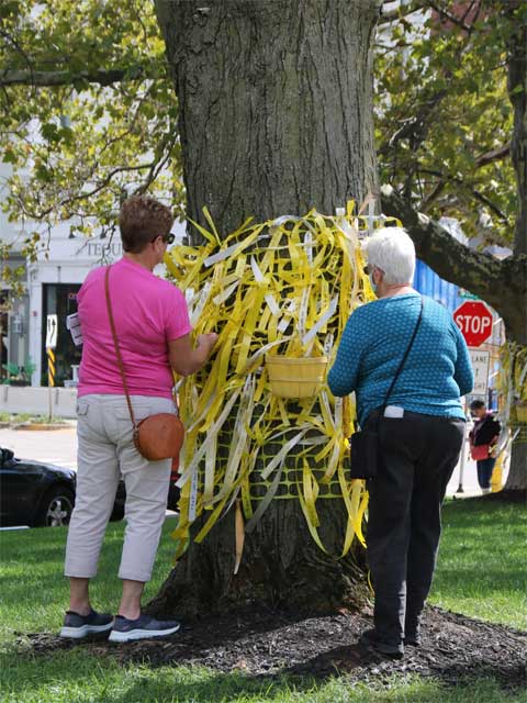 Visitors hanging messages on yellow ribbons at the Voices Project during ArtPrize 2021